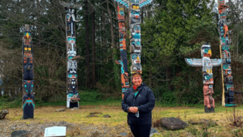 woman standing in front of totem poles