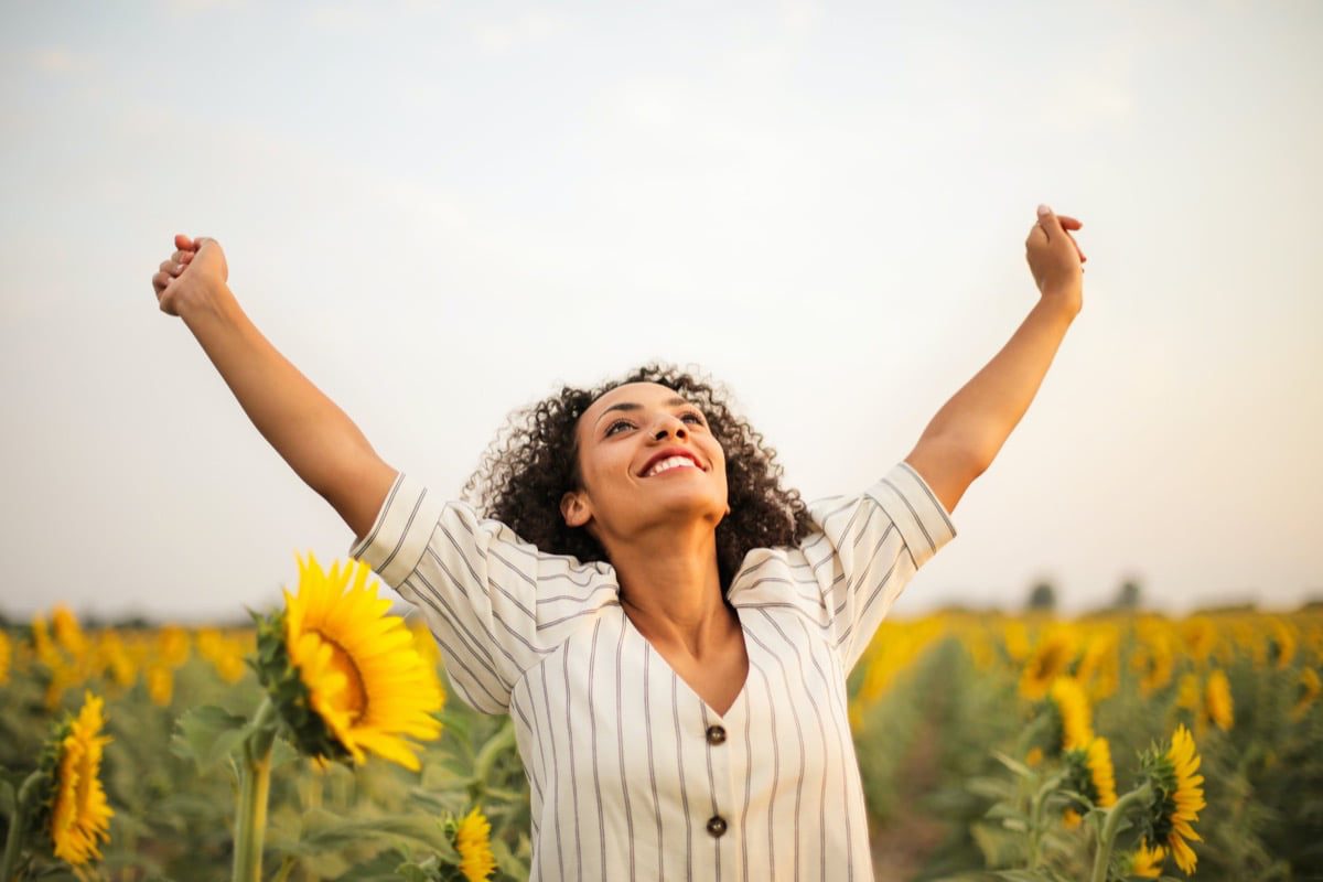 Woman with arms raised in sunflower field - Women over 50 retreats