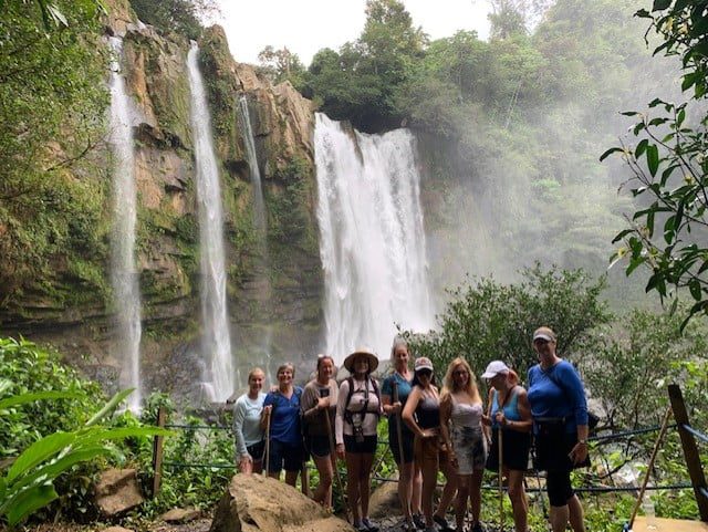 A group of tourists gaze up at a waterfall as part of the Costa Rica Jungles and beaches tour with Women Traveling the World.