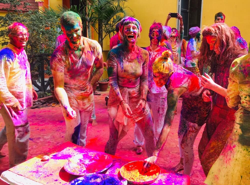 Group of women covered in coloured powder celebrating Holi in India