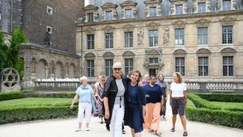 Happy women stand together in front of historic building in Paris