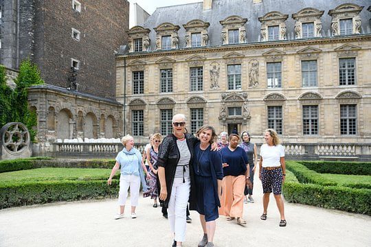 Happy women stand together in front of historic building in Paris