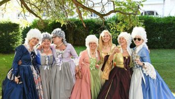 A group of women dressed in period gowns and wigs from the time of Marie Antoinette