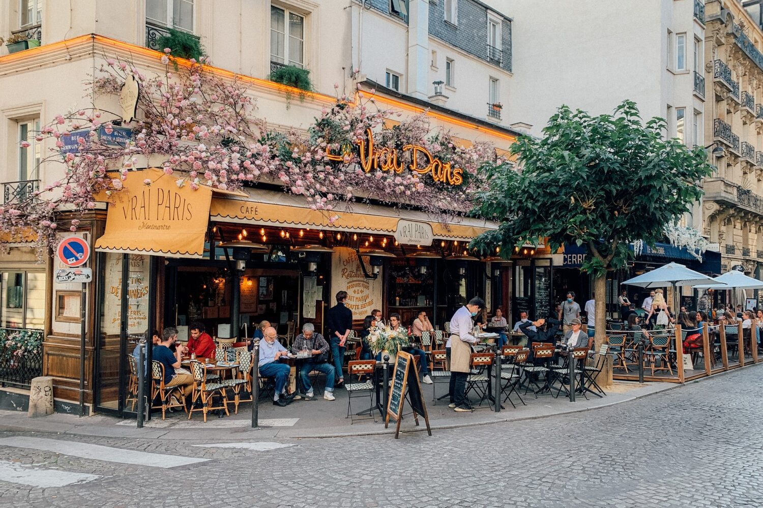 Detail of cafe in paris with flowers and people eating