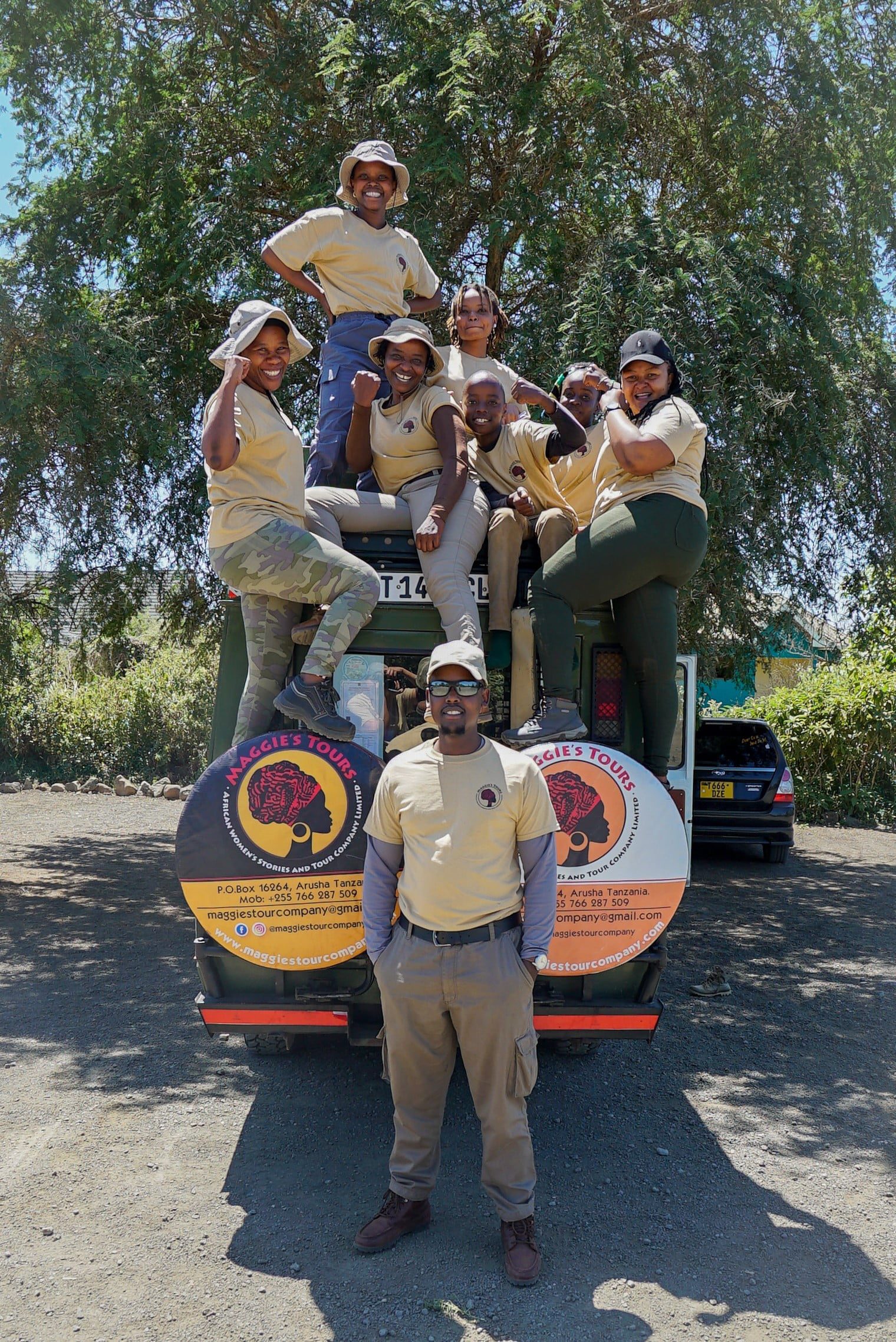 Tour guides who work for Maggie's Tour Company in Tanzania stand together with their safari jeep.