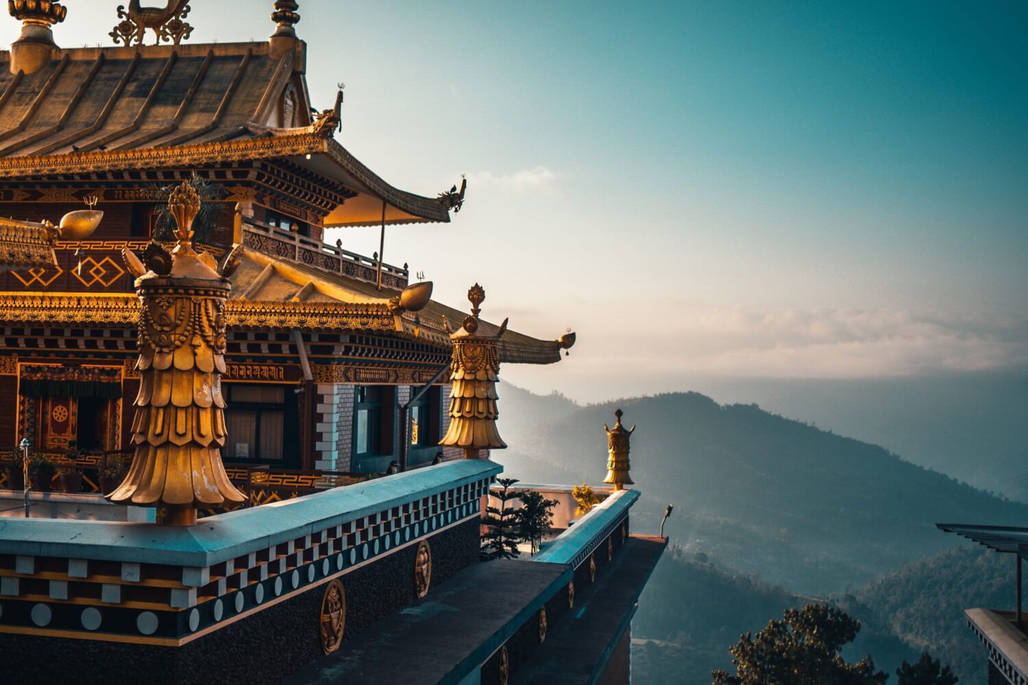 An ornate temple with gold detail overlooks the mountains in the background - Nepal Trail Running and Wellness Retreat - Run Wild Retreats