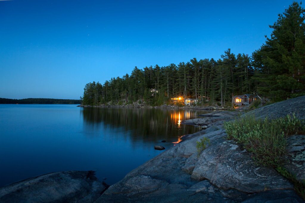 A nighttime view of the Lodge at Pine Cove resting on the French River in Ontario