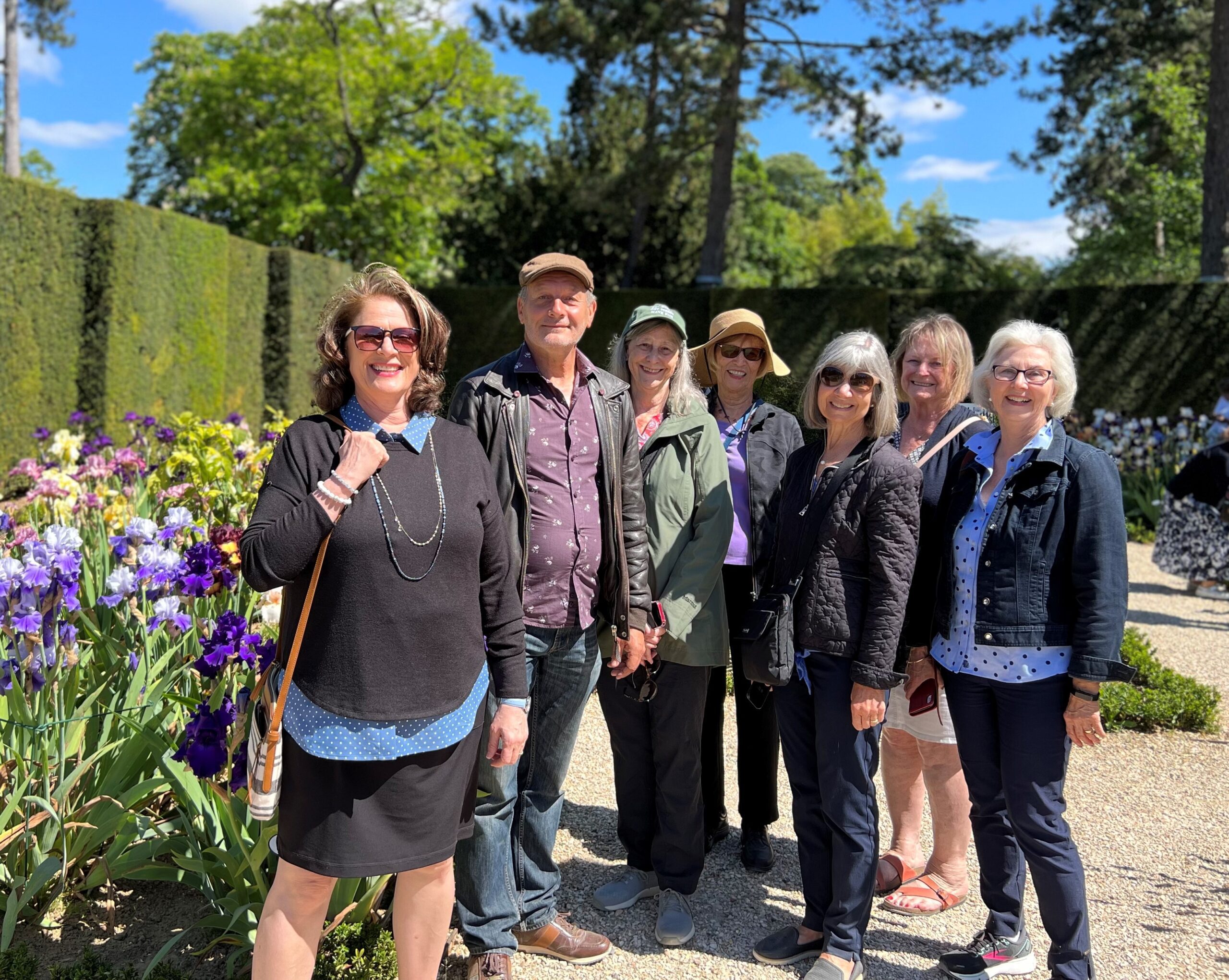 A small group of happy travelers - six women and one man - stand in a garden in Paris. Inside Paris - European Experiences