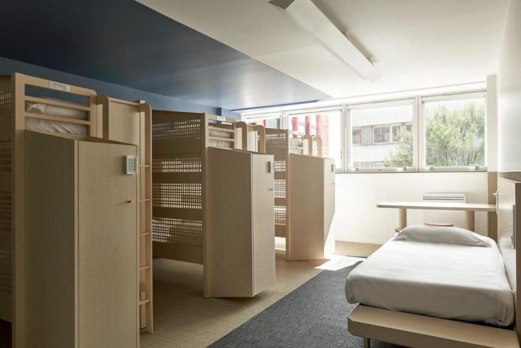 Multiple twin beds separated by privacy screens show one of the sleeping options at luxury hostel FIAP Jean Monnet in Paris, France. Recommended by a reader of the Women's Travel Directory.