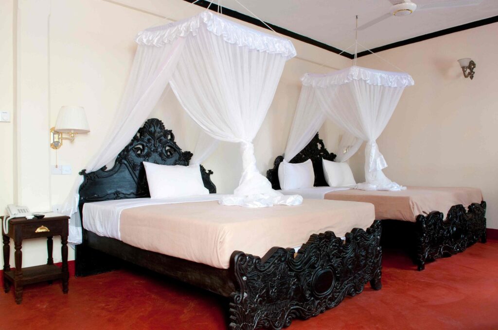An understated and modestly decorated room with two double beds at the Forodhani Park Hotel in Zanzibar, Africa