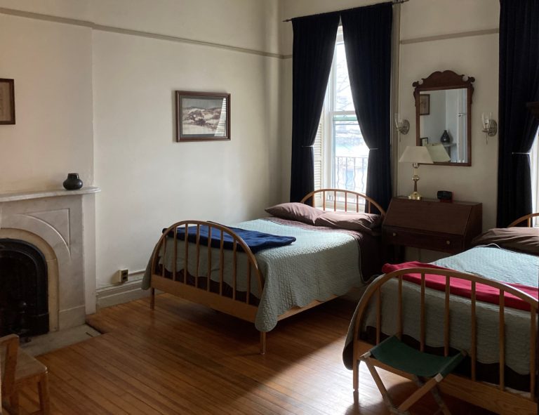 Two twin beds on iron frames in a simple room of the Penington Friends Guest House, a Quaker initiative, in New York, New York. Recommended by readers of the Women's Travel Directory.
