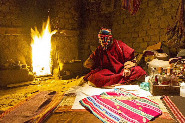 Tate Benjo, a Kallawaya healer, reading the future in sacred coca leaves at the Mystical World of the  Kallawayas Complex  Huatajata, Titicaca Lake, Bolivia