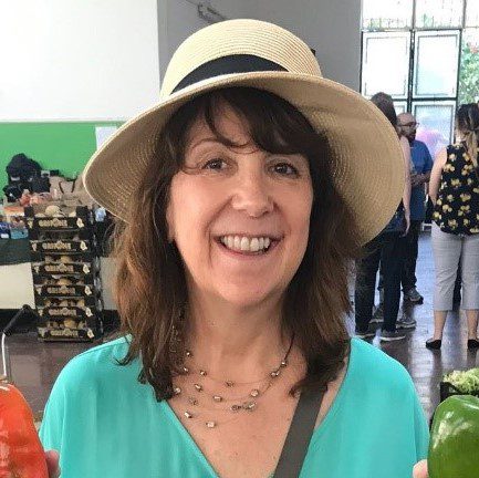 Susan Renke, founder of Global Palate Adventures, smiles for a selfie in a straw sunhat.