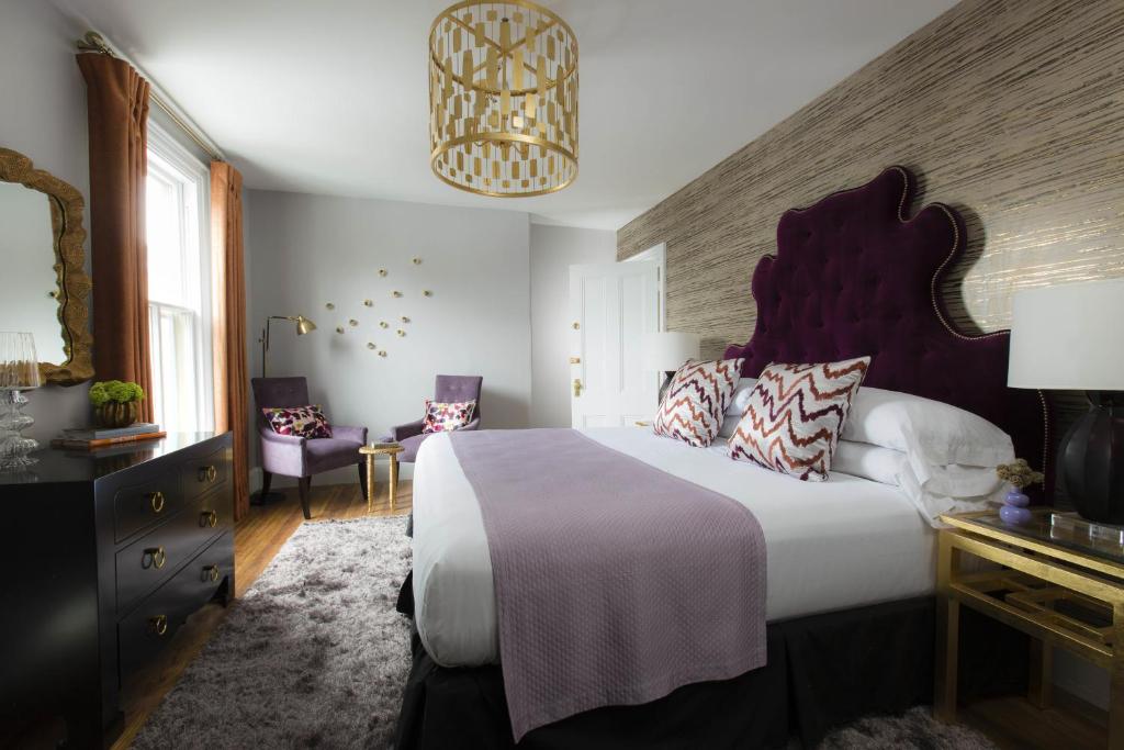 A beautiful double bed suite with ornate, modern chandelier at Gilded, a Lark Hotel in Newport, Rhode Island and a safe place for women to stay.