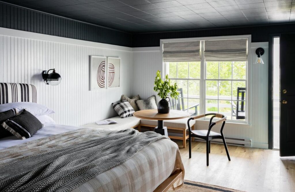 A simple and modern room with a queen bed and seating area at the Bluebird Ocean Point Inn hotel in East Boothbay, Maine.