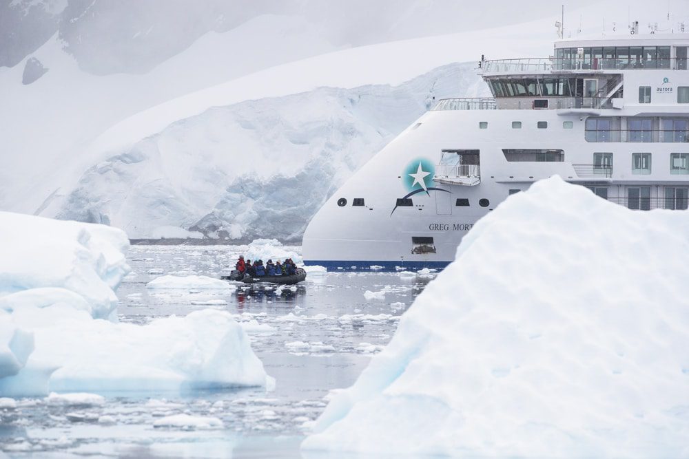 An aerial shot of a ship surrounded by ice, with a Zodiac expedition vessel navigating through the icy waters - Antarctic Explorer