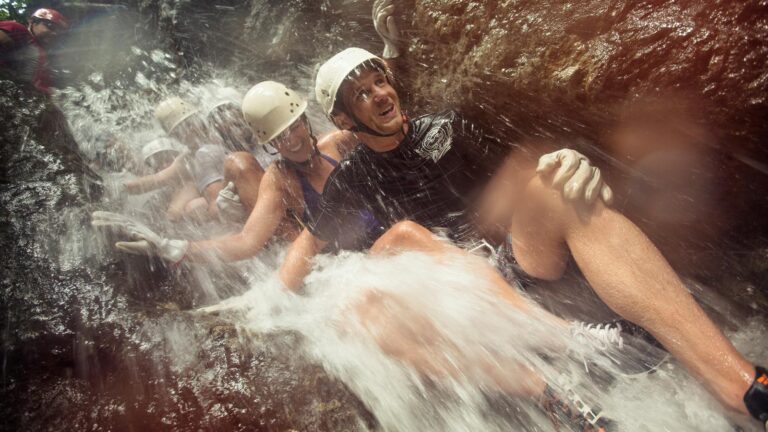 A group of travelers sliding down a cascading waterfall