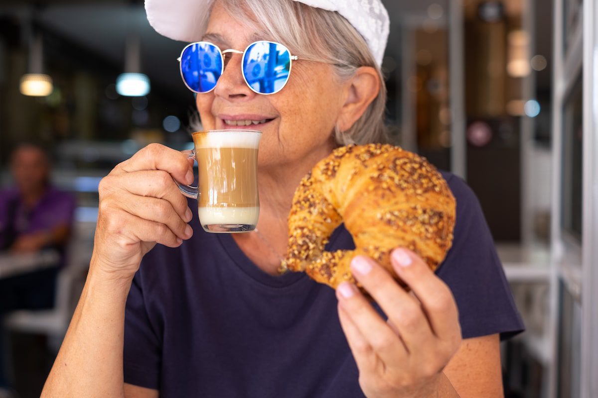 Woman holding a croissant and a coffee