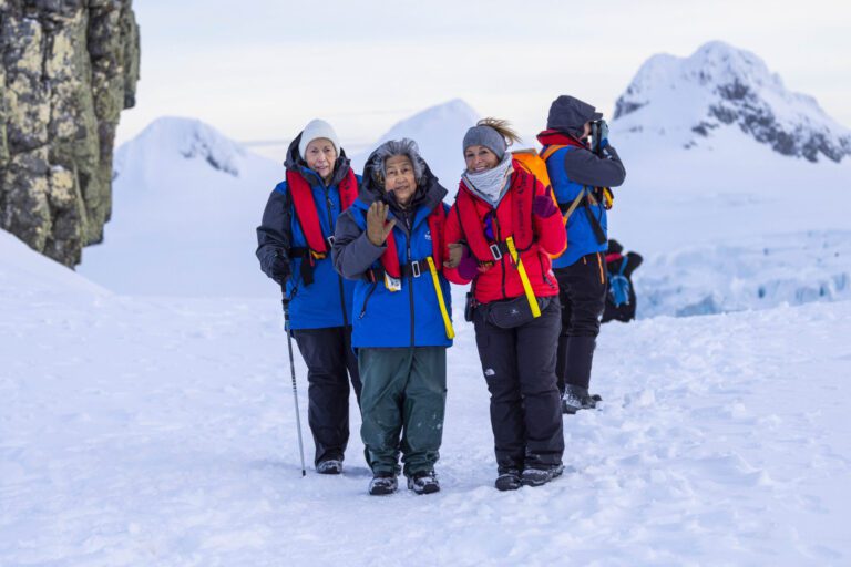 Women dressed in full winter gear pose for a photo on excursion as part of the Antarctic Expedition for Aurora Expeditions