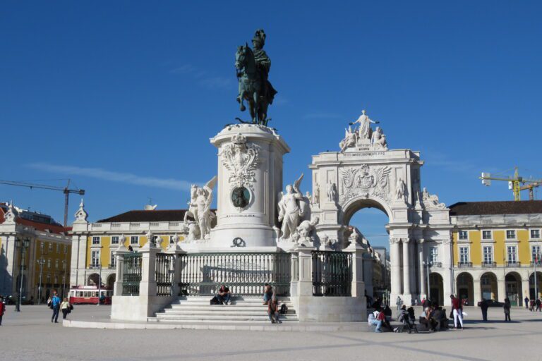 Praça do Comércio in Lisbon, Portugal, featuring the iconic equestrian statue of King José I and the Arco da Rua Augusta under a clear blue sky.