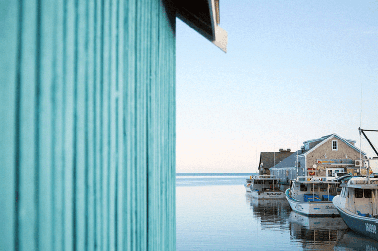 An artful shot of the side of a boat house and docked boats in Prince Edward Island to illustrate the Prince Edward Island: Sea, Soul and Serenity retreat by Divine Destination Collection.