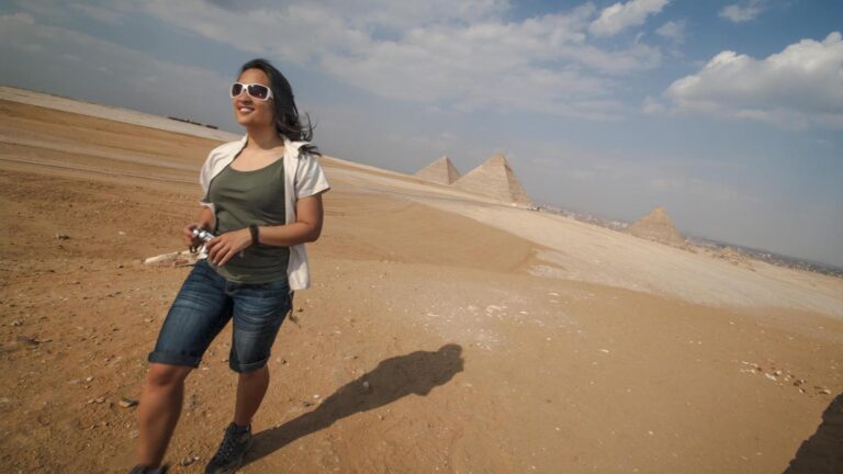 A smiling woman in the desert with pyramids in the background - G Adventures Solo-ish Egypt