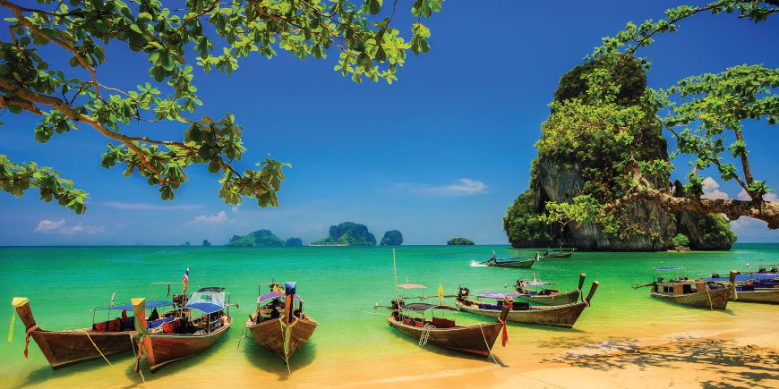 Longtail boats rest along the Phra Nang Beach, a leisure spot on the Thailand - Land of Smiles tour with Just You