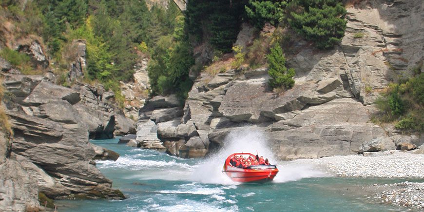 A boat speeds along a glacier river, a part of the Breathtaking New Zealand tour by Just You.