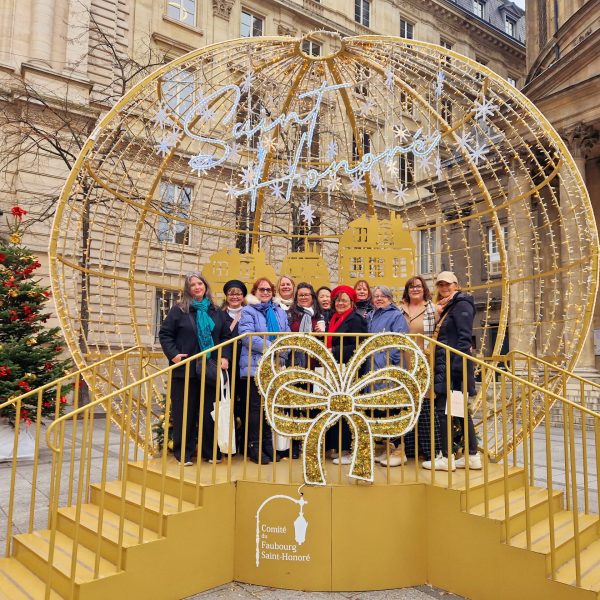 Guests of A Magical Christmas in Paris with bestselling author Steena Holmes posing under festive Christmas decorations.