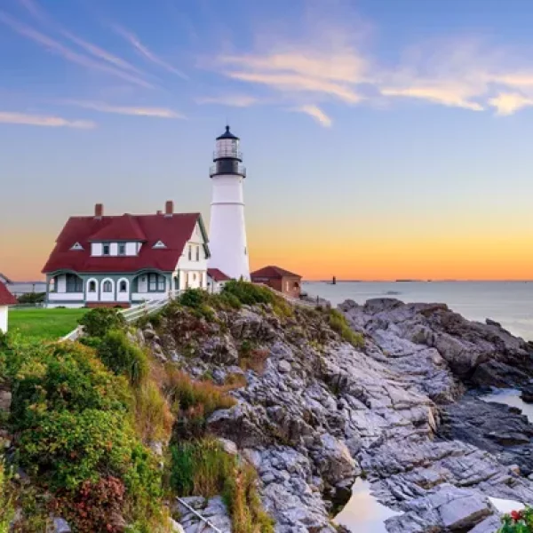 A mesmerizing sunset bathes the iconic Portland Head Light in warm hues, creating a picturesque coastal scene - NEW ENGLAND'S FALL FOLIAGE, A WOMEN-ONLY TOUR - Insight Vacations