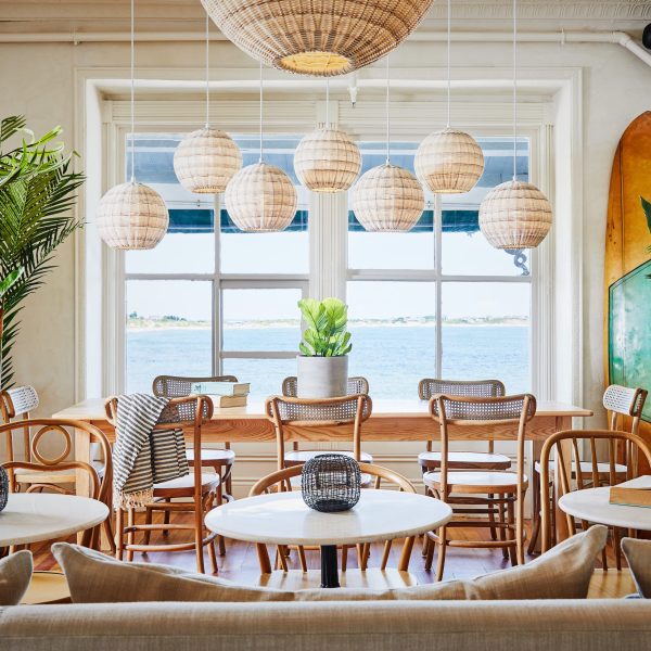 A brightly lit eating area that looks out over the bay to illustrate the Lark Hotels brand.