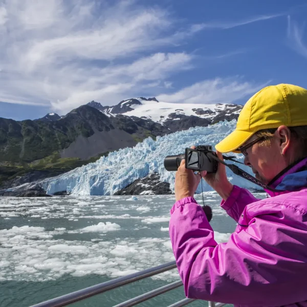 Woman capturing a photo of majestic Alaskan glaciers