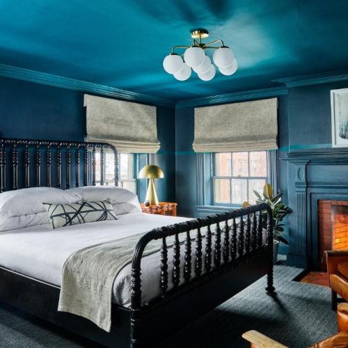 A moody blue bedroom with a double bed at the Blind Tiger guest house in Portland, a Lark Hotel, and a safe place for women to stay.