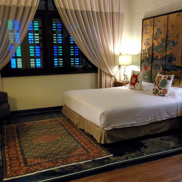 A simple room with beautiful rug and sheer curtains at the Campbell House Hotel Penang in George Town, Malaysia, recommended as a safe place for women to stay by JourneyWoman readers.