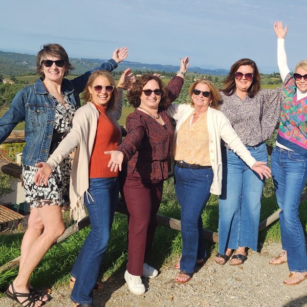 A joyful group of women bonding and relaxing during the Women's Wanderlust Retreat in the picturesque hills of Tuscany.