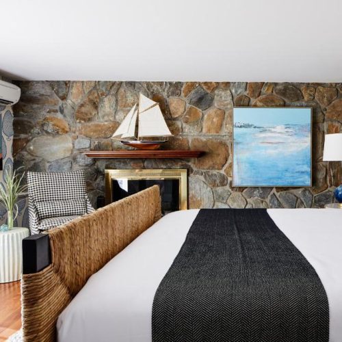 A double bed suite with a nautical theme and rustic stone wall detail at The Cliffside Inn in Newport, Rhode Island, a safe place for women to stay.