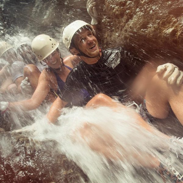 A group of travelers sliding down a cascading waterfall