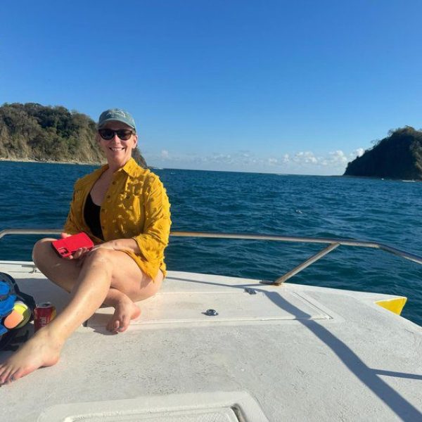 A smiling woman in a yellow top sits on a sailboat enjoying her Costa Rica Adventure with Bold Spirit Travel.