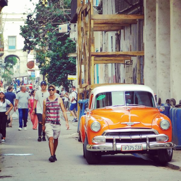 Walking through the streets of Havana, walking next to a classic car, characteristic of Cuba - Joyride Charters
