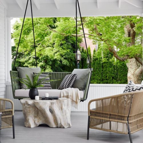 A hanging bend and wicker seating on a porch at the Edgartown Inn—Edgartown Collection by Lark Hotels in Martha's Vineyard, a safe place for women to stay.