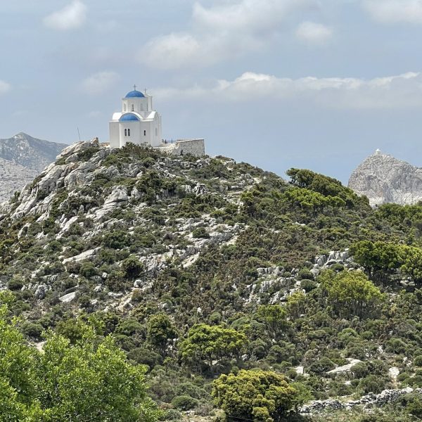 A classic Greek blue-domed building sits atop a rocky hill - Island Hopping the Greek Islands - Adventures in Good Company