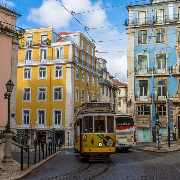 Two trams passing through the colorful streets of Lisbon, surrounded by vibrant buildings and historic charm