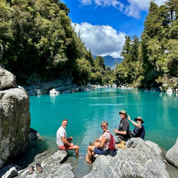 A group of women enjoying the breathtaking view of a serene lake surrounded by lush greenery and distant mountains