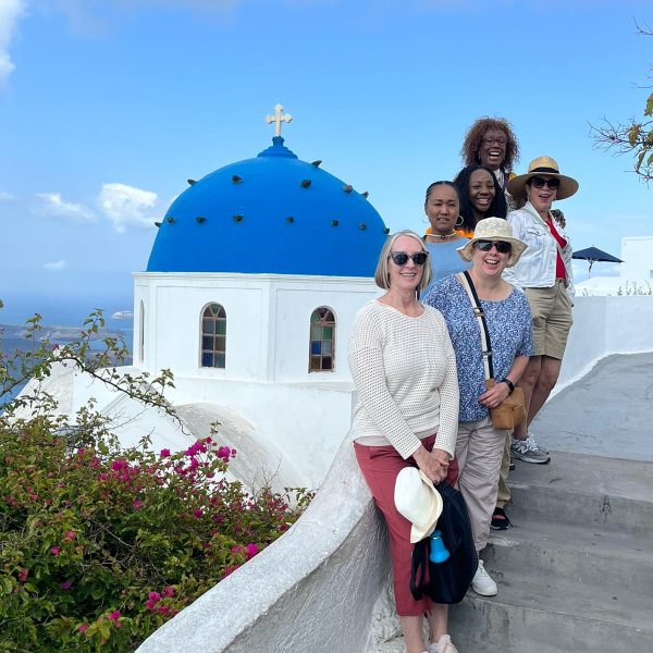 A group of people enjoying a rooftop in Santorini, surrounded by iconic blue-and-white architecture.