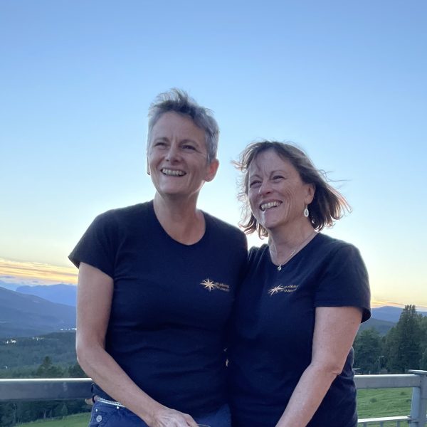 Sisters and owners of WalkingWomen Ginny and Sara pose for the camera with an early sunset view in the background.
