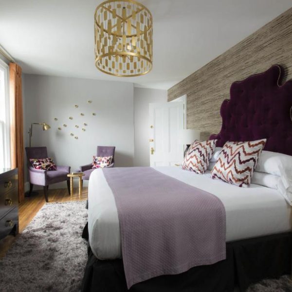 A beautiful double bed suite with ornate, modern chandelier at Gilded, a Lark Hotel in Newport, Rhode Island and a safe place for women to stay.