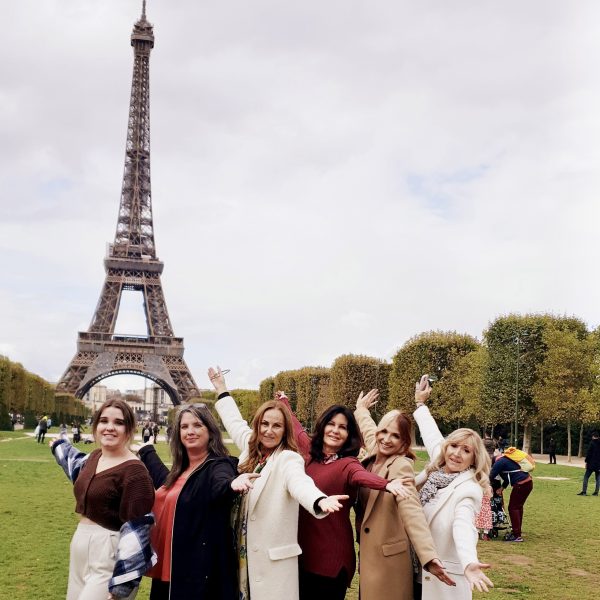 Group of women posing in front of the iconic Eiffel Tower, a highlight of the Perfect Paris Tour.