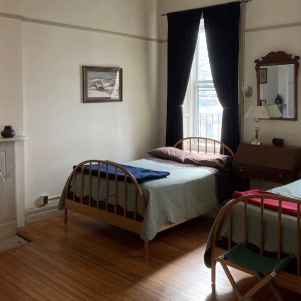 Two twin beds on iron frames in a simple room of the Penington Friends Guest House, a Quaker initiative, in New York, New York. Recommended by readers of the Women's Travel Directory.