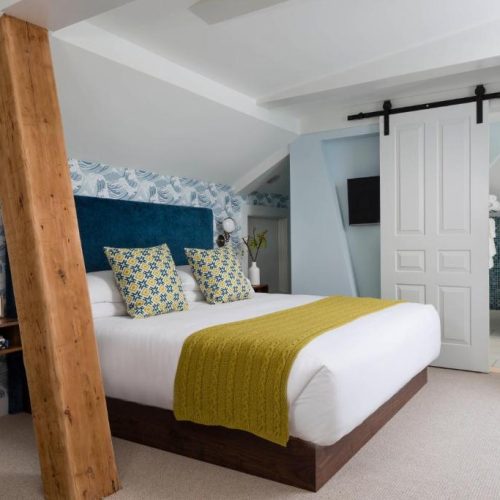 A bedroom suite with unique features at The Merchant Salem, a Lark Hotel, and a safe place for women to stay in Salem, Massachusetts.