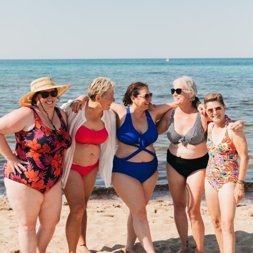 Five mature women pose in beautifully colorful swimsuits on an Italian beach - Stellavision Travel